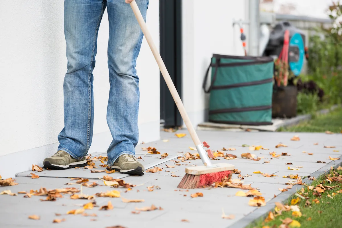 Lichtschachtabdeckung auf Terrasse Mann fegt Laub